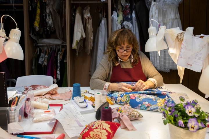 Una especialista en costura a medida da forma a una falda estampada de flores sobre fondo azul Prusia.