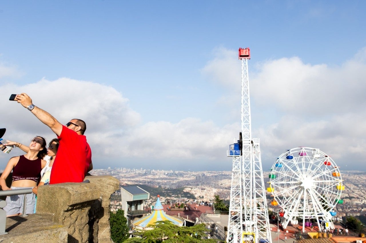 Barcelona. 1/7/18. Selfie en el Parque de atracciones del Tibidabo. En la imagen, una familia se hace una fotografía selfi desde el Templo del Sagrado Corazón de Jesús, con vistas a la Atalaya y el Giradavo. Foto de César Cid