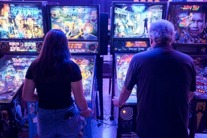 Un hombre y una joven juegan con las pinballs.