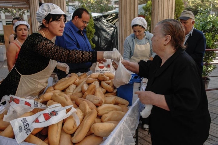 Repartiendo los panecillos que acompañan al guiso de la festividad del Santo Voto, en Puertollano, Ciudad Real.