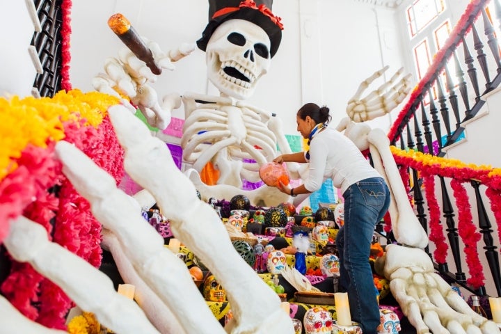 Carmen Rosas, encargada de los talleres de artesanía, completando la ofrenda a los difuntos con pan de muertos, cuyo aroma flota en el 'hall'.