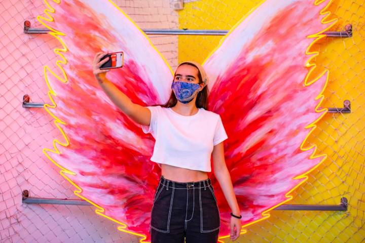 Una chica se hace un selfie con alas de mariposa.