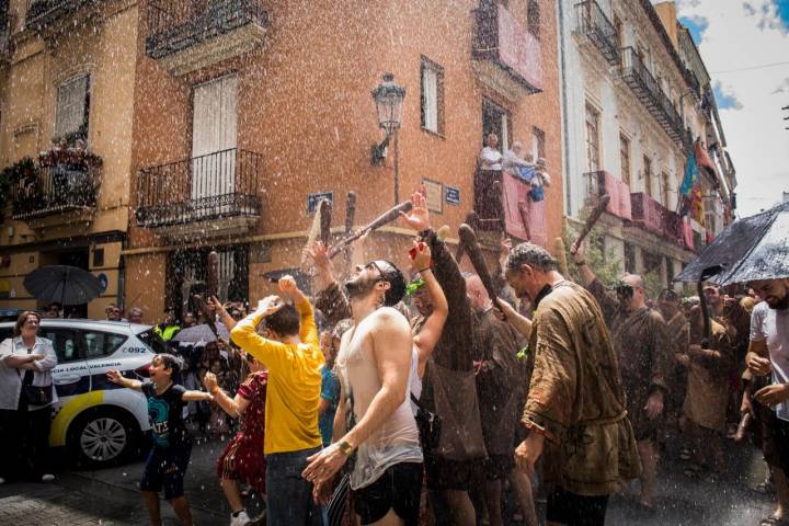 Visitantes y miembros de la Degolla mojados en la calle Avellanas durante la Cabalgata del Convite.
