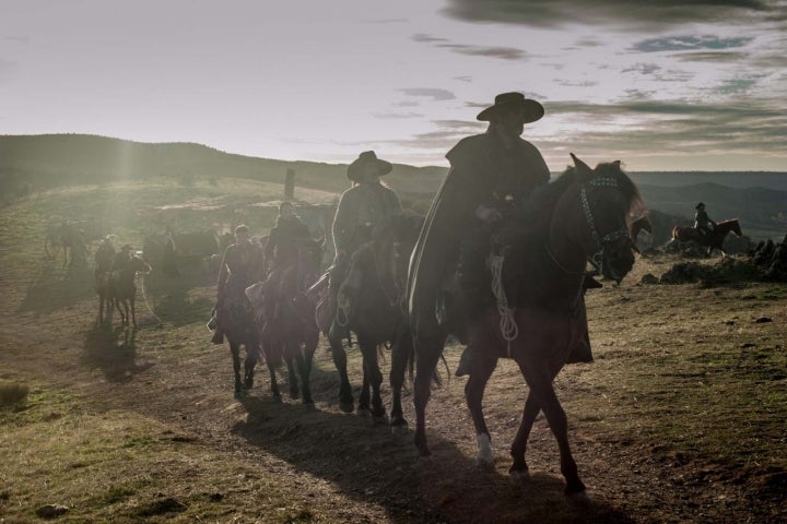 Varios jinetes a caballo por la montaña.