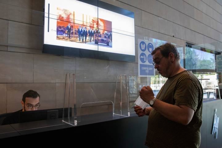 Un trabajador atiende desde los mostradores a uno de los hombres que han acudido a visitar el museo.