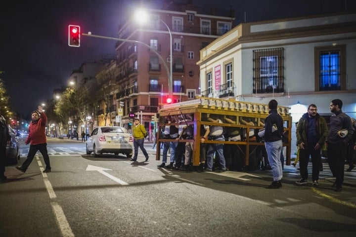 El equipo de capataces de la Hermandad de El Amor controla el tráfico mientras la parihuela cruza la avenida.