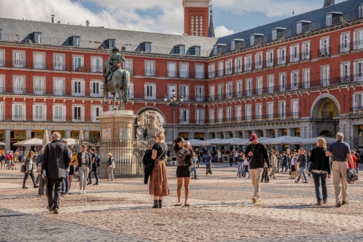 Madrid /Spain - October 14, 2019:  Young women explore and take photos on a busy day in Plaza Mayor, a beautiful and historic plaza in central Madrid.