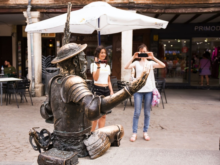 Turistas fotografiando el banco del Quijote de Alcalá de Henares (Madrid).