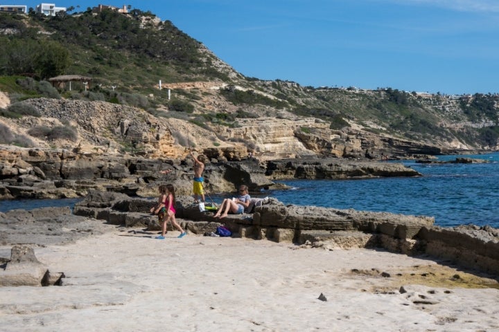 Una familia con un niño y una niña buscan cangrejos entre las rocas de una de las piscinas naturales