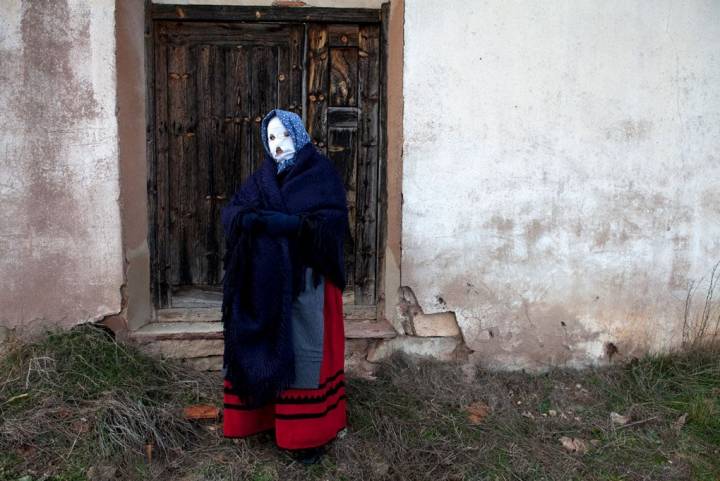 Un mascarita posa ante una de las puertas del pueblo.