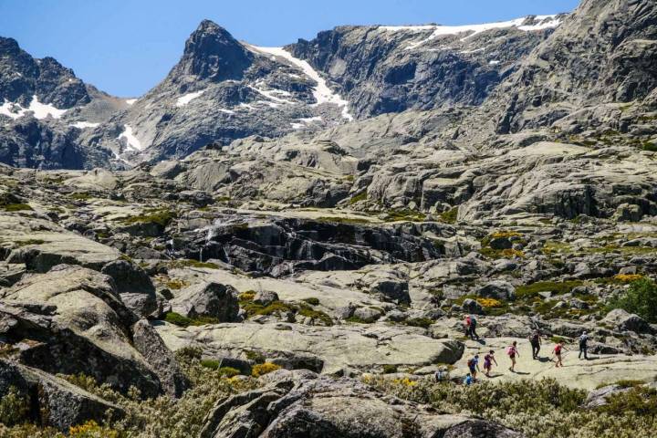 Senderistas subiendo por las enormes rocas que marcan la cima de la Sierra de Gredos.