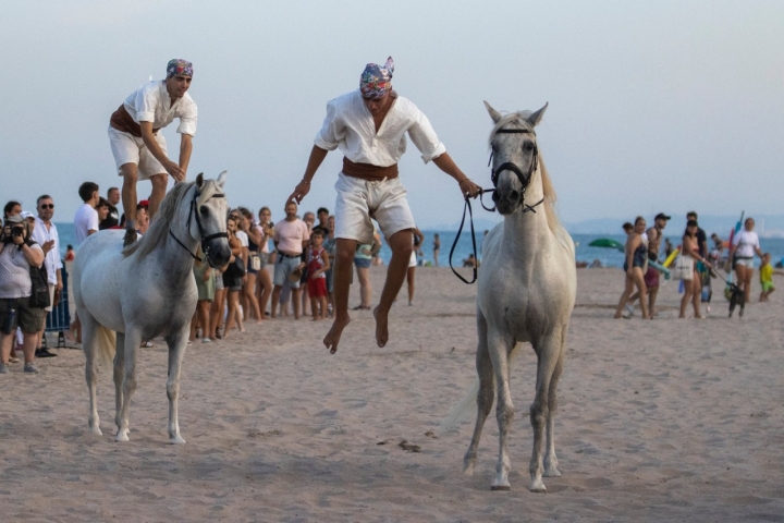 Los jinetes hacen acrobacias con y sobre sus caballos.