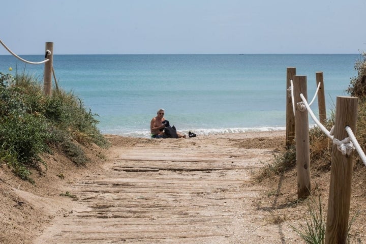 Un hombre toma el sol a la orilla de la playa en El Saler (Parque Natural La Albufera, Valencia).