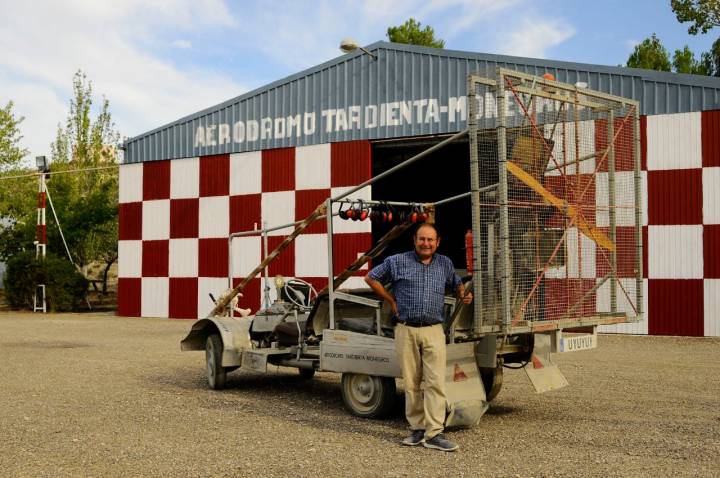 José Manuel Ayuda posa delante de uno de sus dos hangares y junto al vehículo el 'Pájaro uyuyy'.