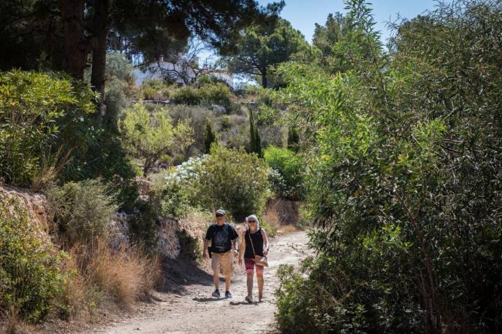 Una pareja de turistas camina por el paseo ecológico de Calpe, en Alicante.