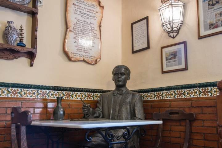 Una de las mesas del salón del restaurante 'Chikito', con una estatua del poeta Federico García Lorca.