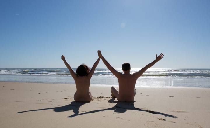 Dos personas desnudas en la orilla de una playa