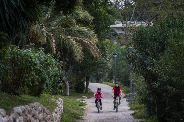Un padre y una hija pasean en bici por la ladera del río Vinapoló, en Elche (Alicante).