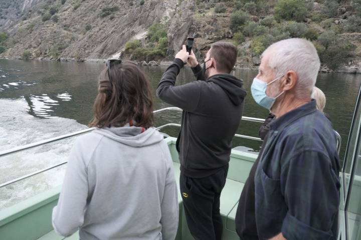 Varios pasajeros, de pie, hacen fotos del Duero y sus orillas.