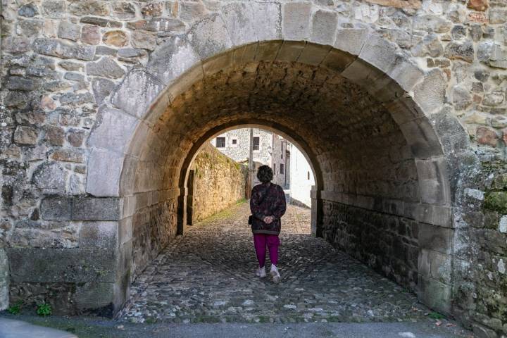 Una mujer bajo un arco de piedra en Cosío (Cantabria)