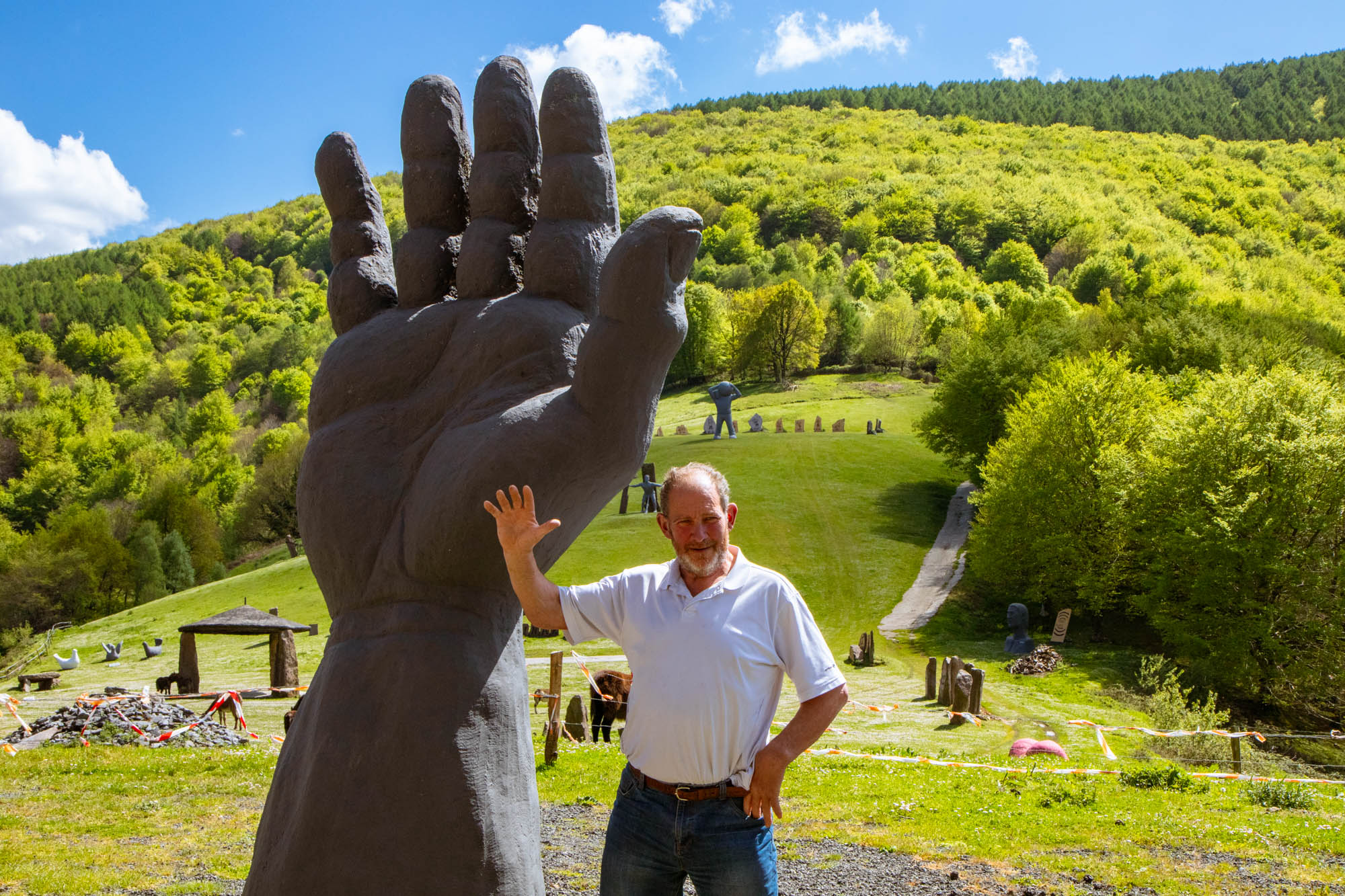 Iñaki Perurena muestra su mano derecha, que fue el modelo para hacer una enorme escultura frente al caserío.