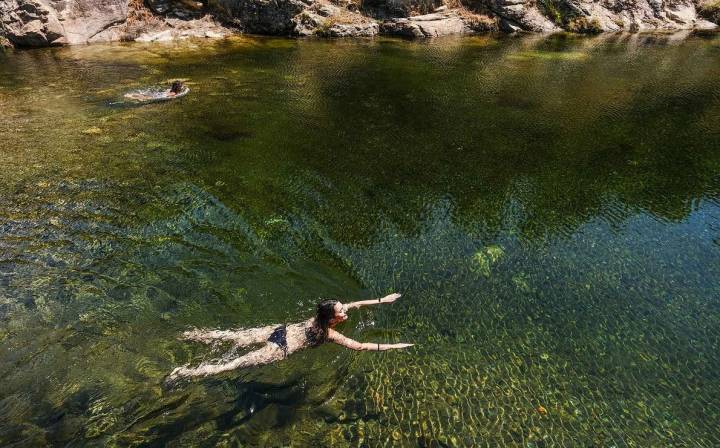 Una mujer nada en las aguas cristalinas de la piscina de Jevero en Acebo, el norte de Cáceres.