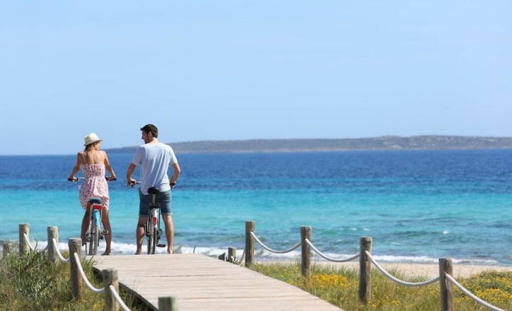 Una pareja dando un paseo con la bicicleta con el mar de fondo.