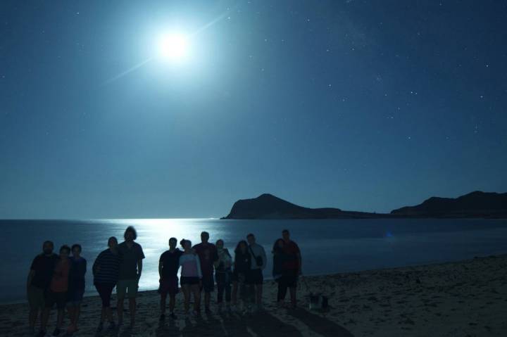 Un grupo de gente en la playa por la noche posando para una foto.