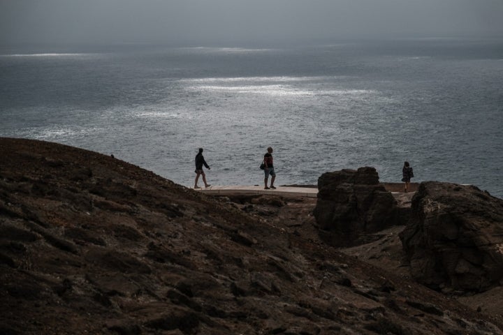 Tres personas caminan por el sendero del Confital.