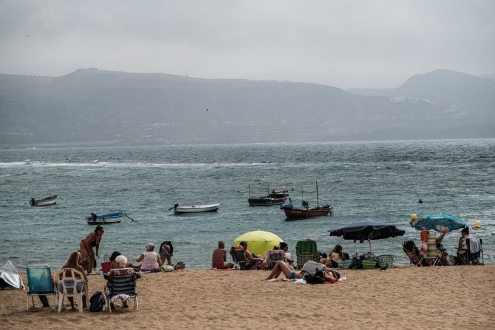 Gente con sus sombrillas y tomando el sol en la playa de Las Canteras.