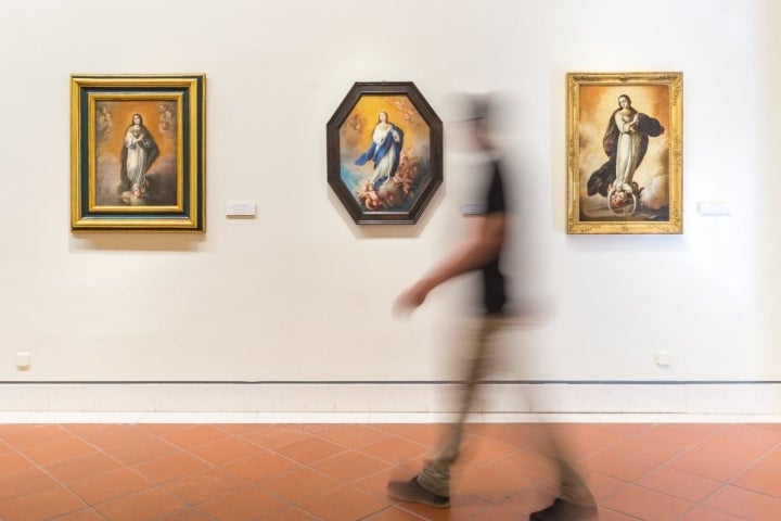 Un visitante recorre una de las salas del Museo de Bellas Artes de Sevilla donde cuelgan varias Inmaculadas de Murillo.