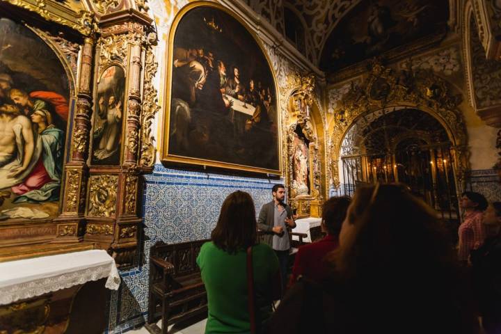 El guía muestra el cuadro de La Santa Cena de Murillo en la iglesia de Santa María La Blanca durante la visita nocturna, en Sevilla.