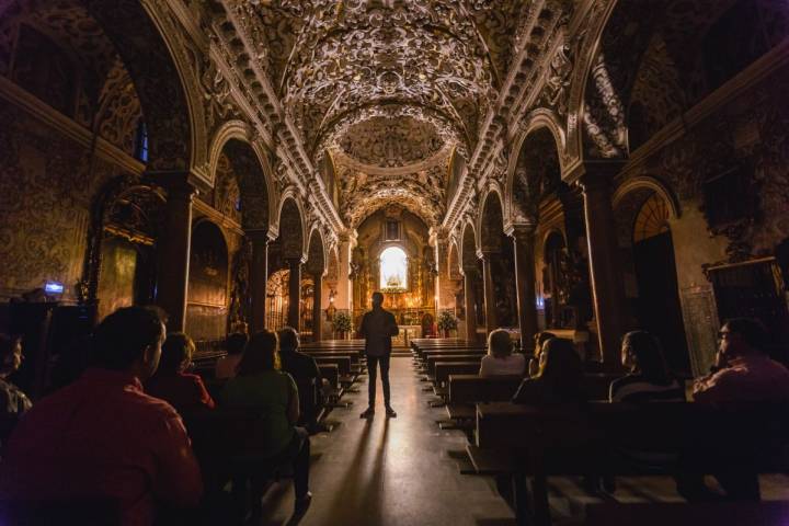 El guía recibe en el interior de la iglesia Santa María La Blanca, de Sevilla, durante la visita nocturna.