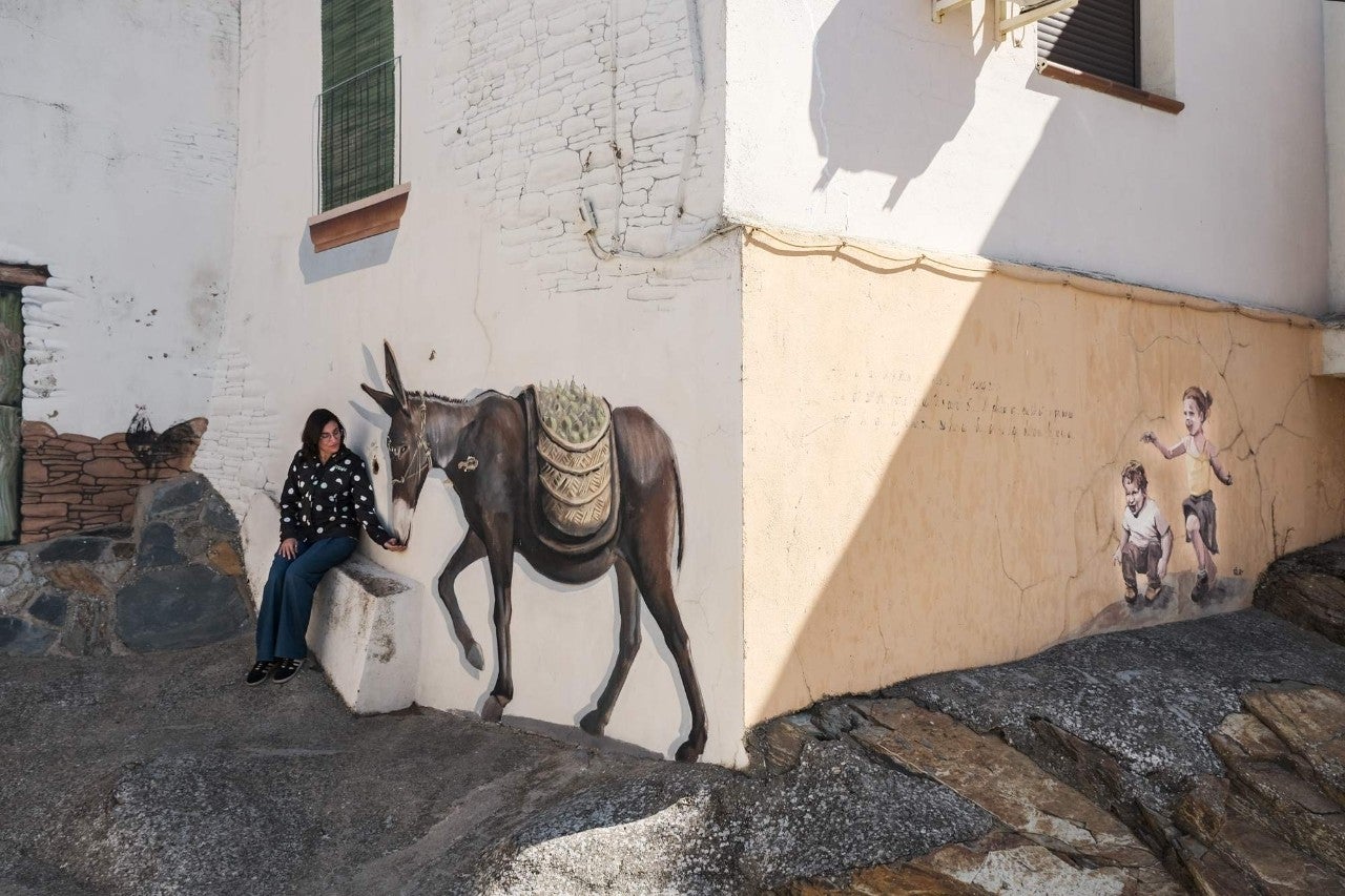 Una mujer sentada junto a un burro dibujado.