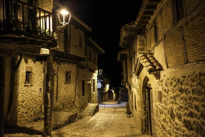 Una calle iluminada y solitaria del pueblo de Calatañazor durante la noche.