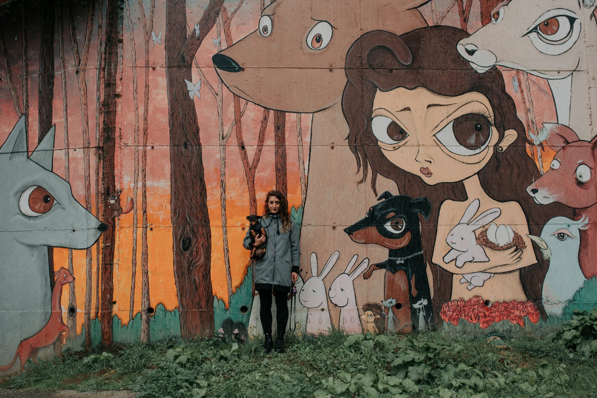 La artista Nana posa, junto a su perra Montana, frente a su obra 'Incendios nas Fragas do Eume' (2012) en Ordes.