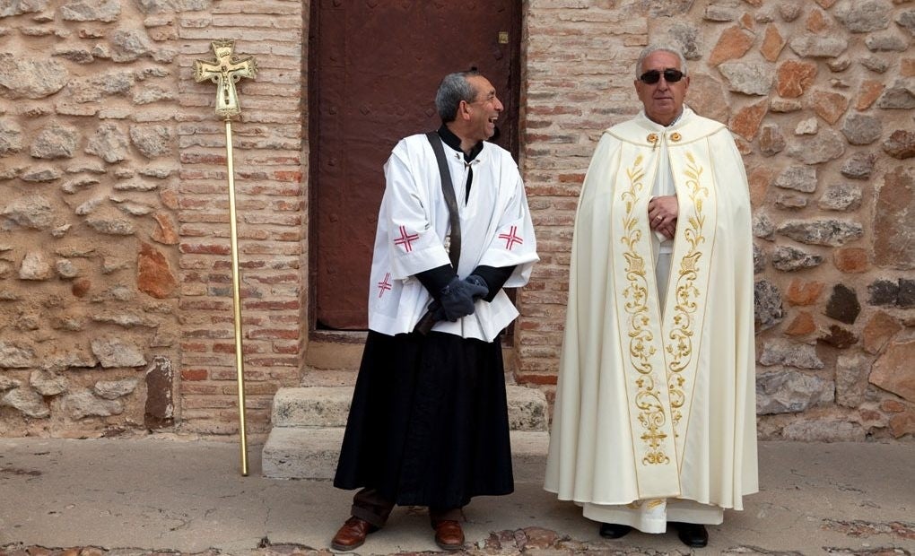 Antes de la procesión del Jueves Santo, el sacristán bromea con el párroco de Aldea del Rey.