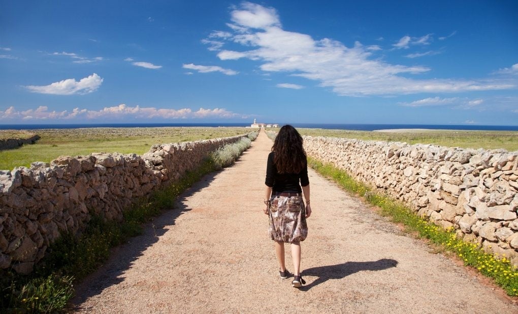 Mujer paseando por un paisaje naturista de Menorca