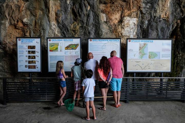Una familia lee los paneles informativos a la entrada de la cueva.