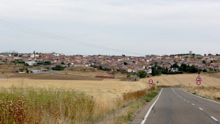 Carretera de acceso con el pueblo al fondo. Fotografía: Ángel Encinas Carazo vía Wikipedia / CC BY-SA.
