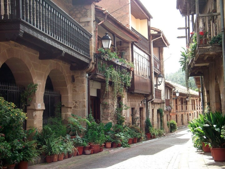 Calle principal de Cartes, con sus bellas casas engalanadas con flores. Fotografía: Codigowiki vía Wikipedia / CC BY-SA.