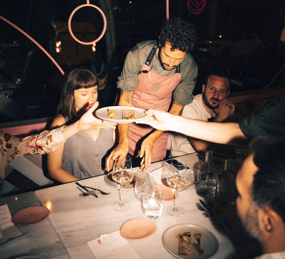camarero sirviendo a una mesa llena de comensales durante una cena